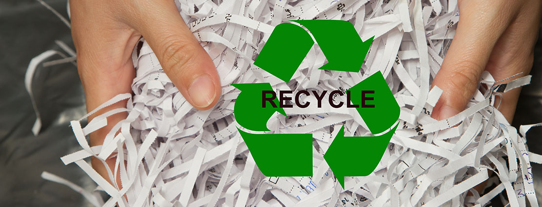 Shredded Paper being held with Recycling Logo on top