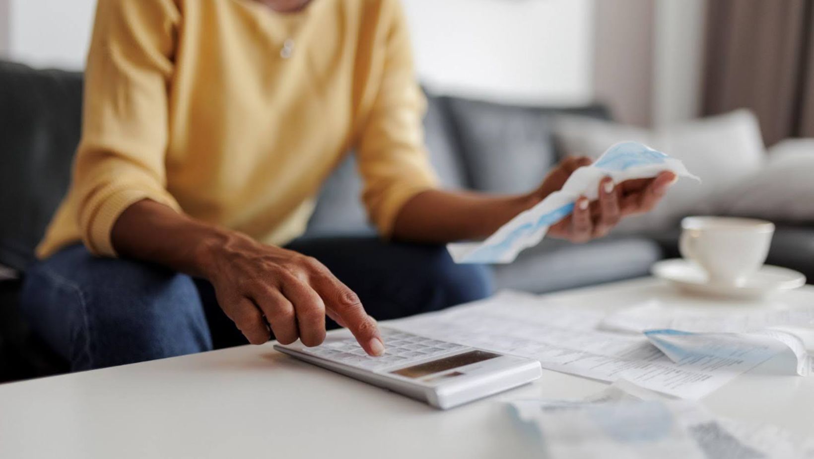 Person sitting down with a calculator and bills for tax day