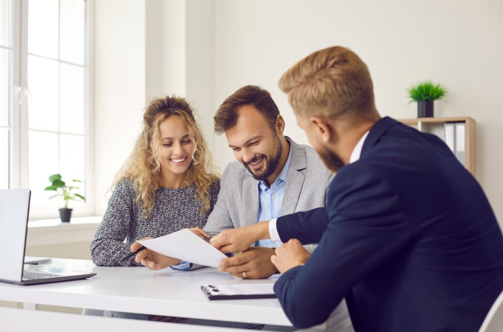 A couple signing documents with their insurance agent