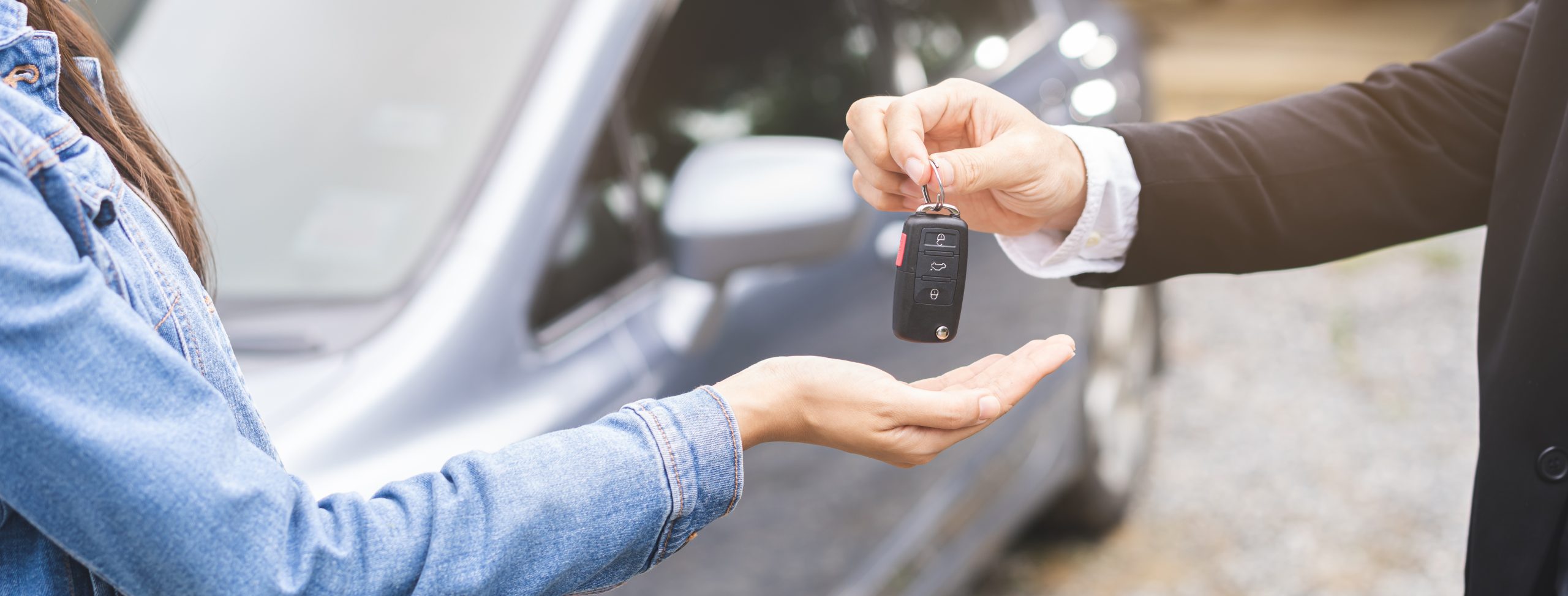sale man giving auto key of vehicle to customer