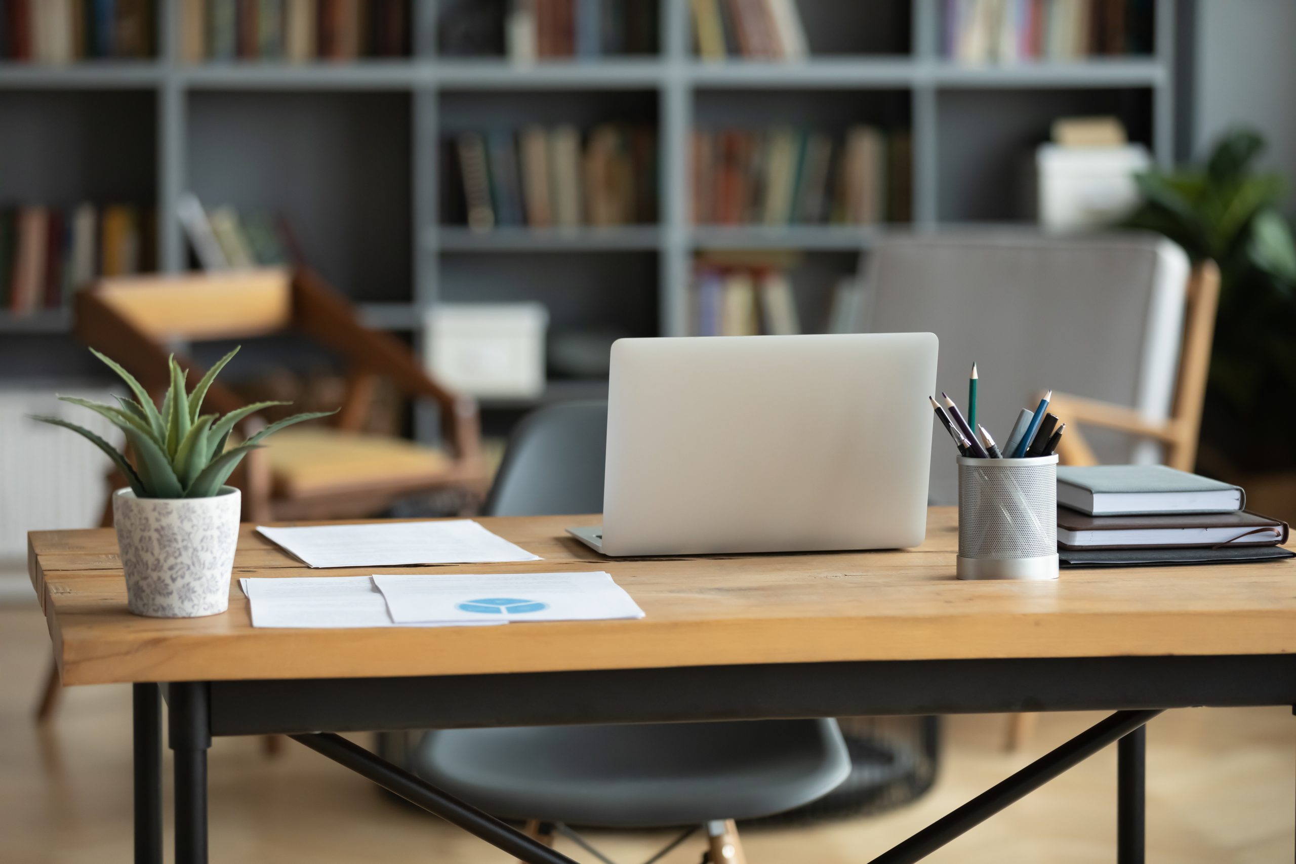Wooden work desk with laptop and documents, modern interior
